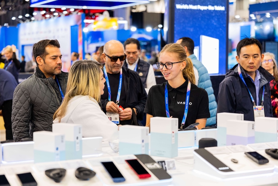 Skupina usmiatych ľudí sa rozpráva pri stánku spoločnosti Vasco Electronics na veľtrhu CES 2026.