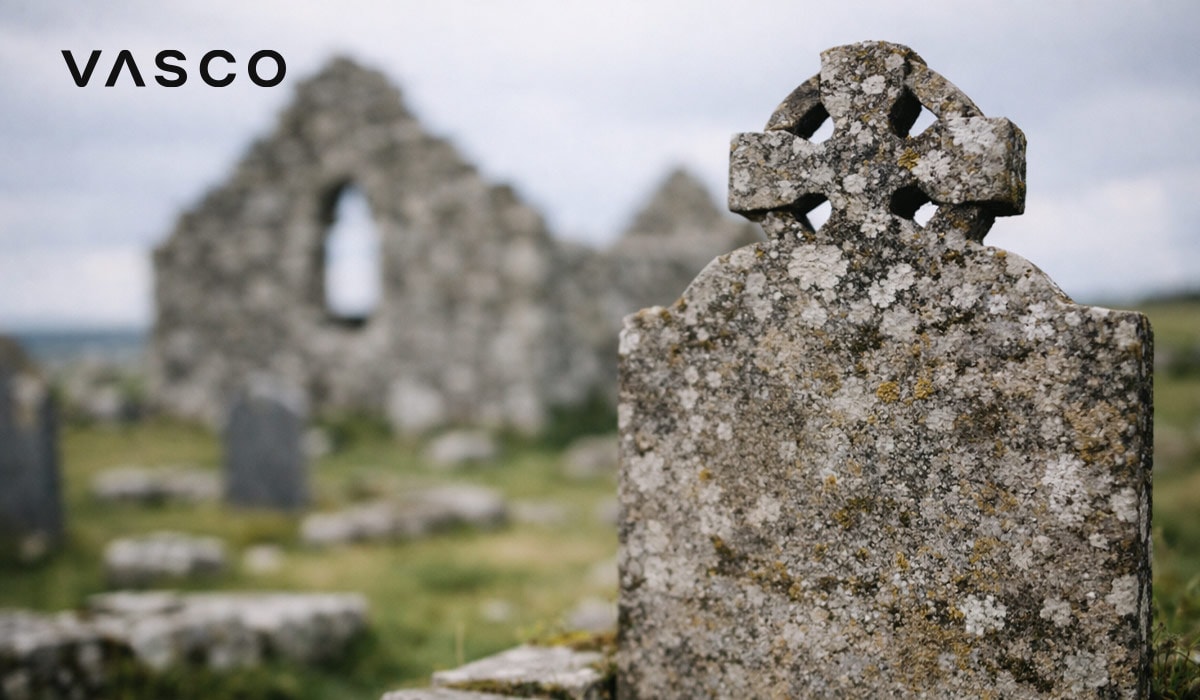 Zvetraný keltský krížový náhrobný kameň blízko starých kamenných ruín