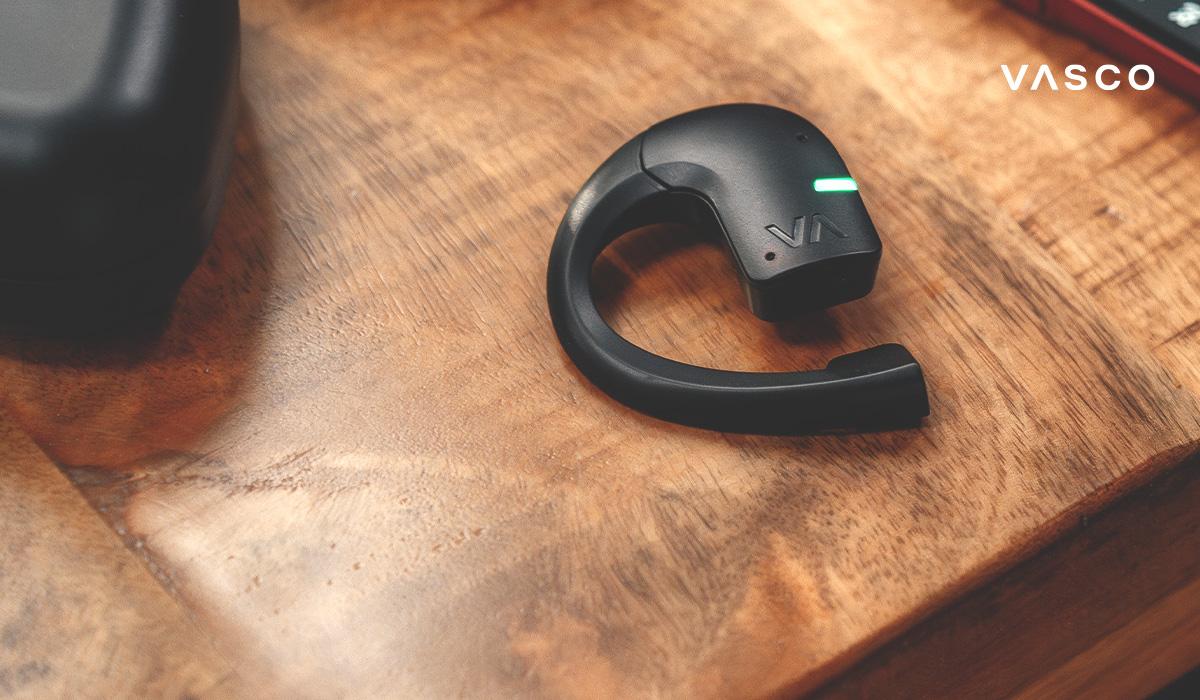 Detailný záber na slúchadlo Vasco Translator na drevenom stole s LED indikátorom