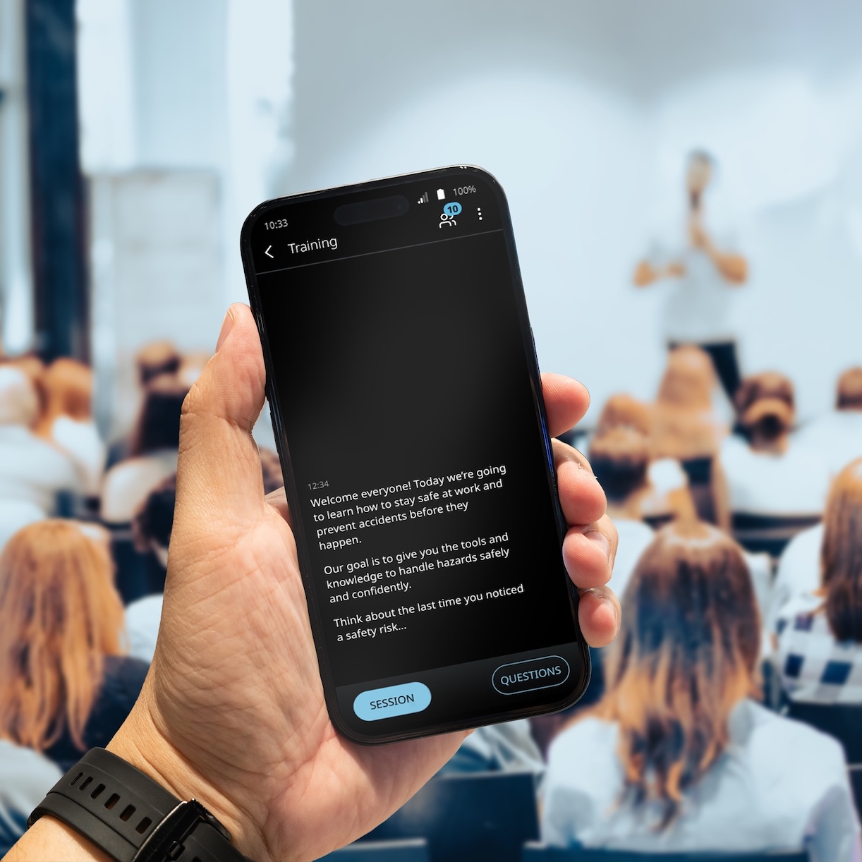 Vasco Audience V sále plnej ľudí prebieha prednáška. Muž drží v ruke telefón, na ktorom sa pomocou aplikácie Vasco Audience zobrazuje preklad.